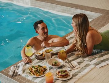 Two people eat and soak poolside at The Kenrick Hotel.