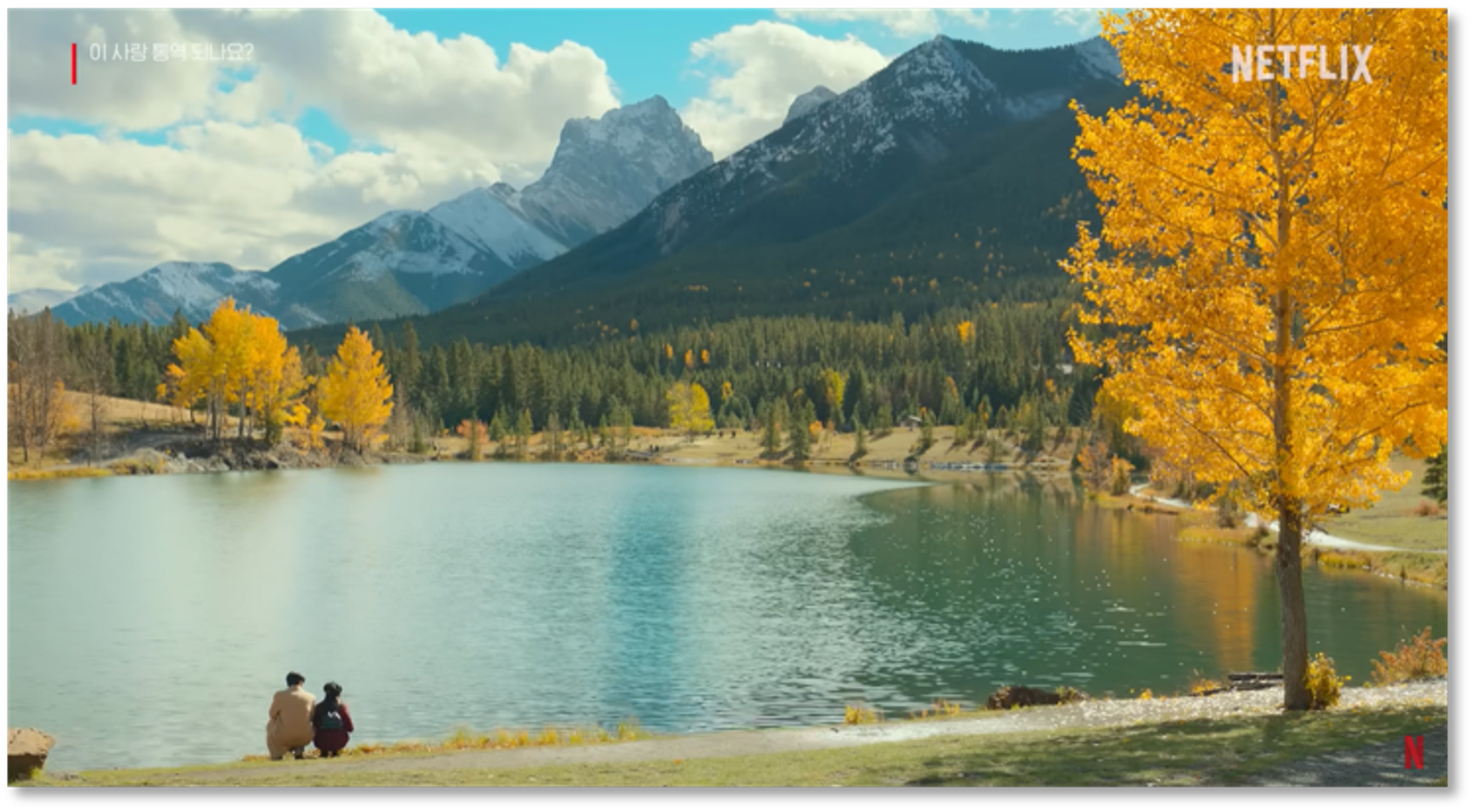 Characters sit at the edge of Quarry Lake with golden trees and mountains all around.