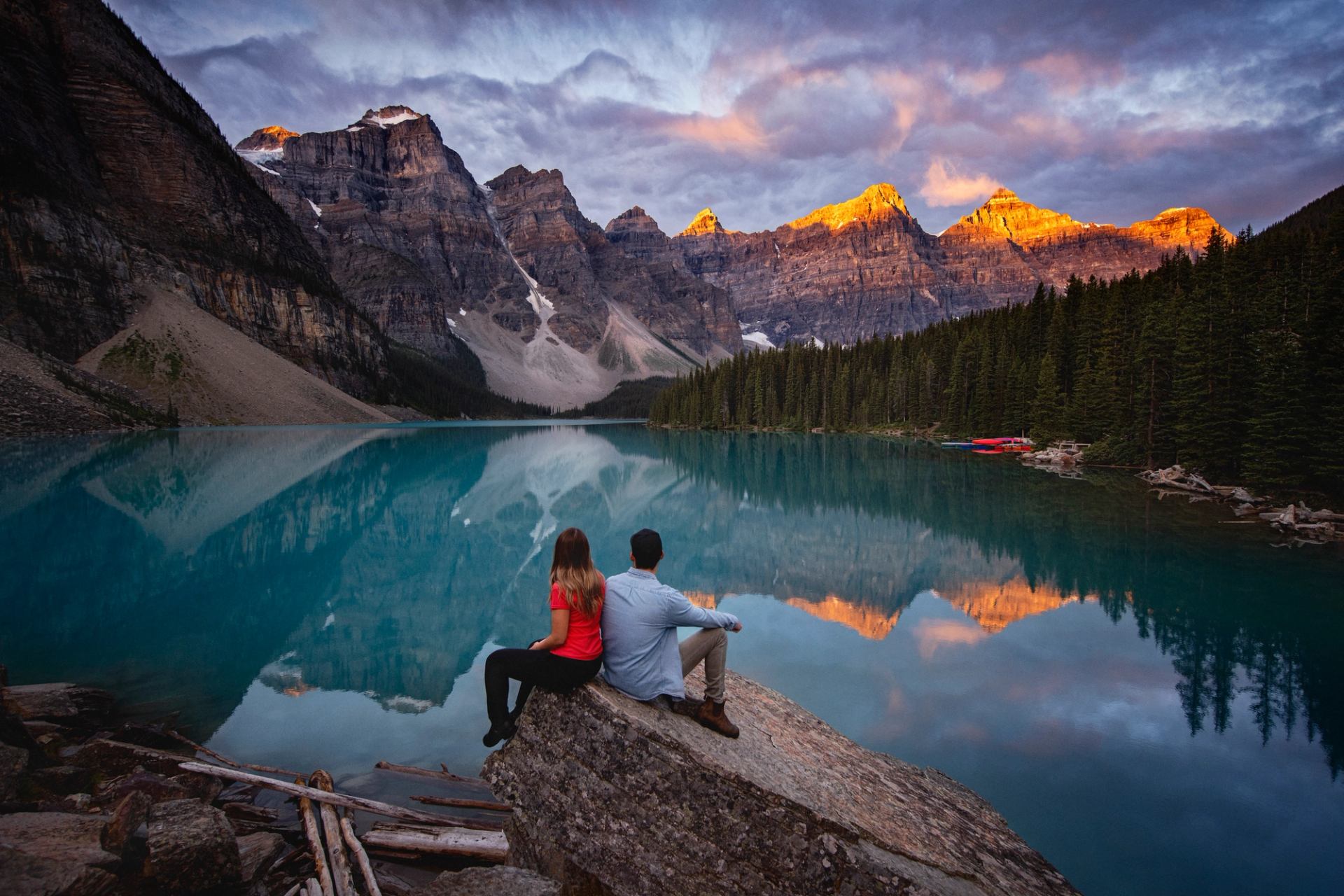 Travellers enjoy the view of vibrant blue Moraine Lake surrounded by the Valley of the Ten Peaks.