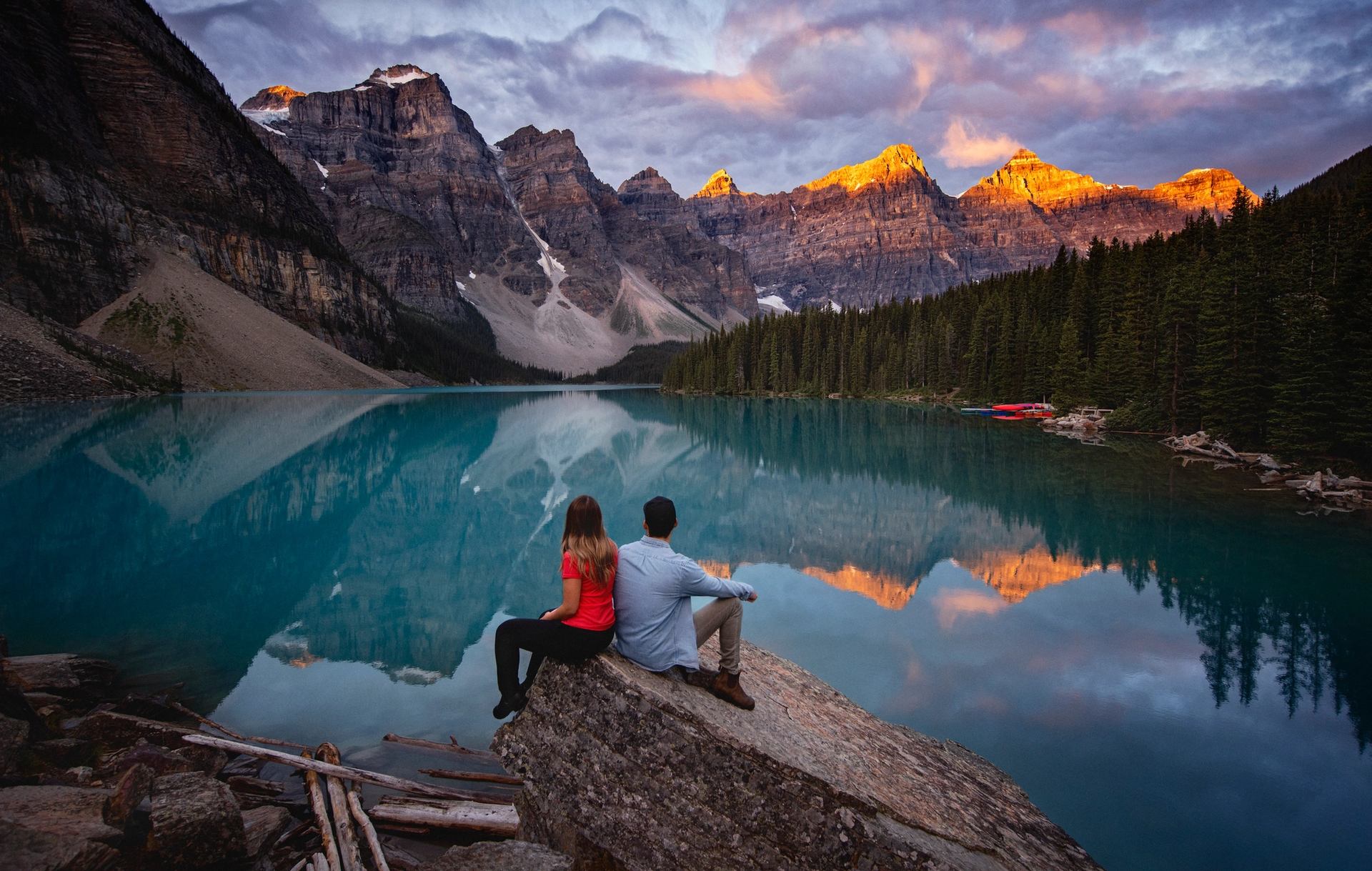 Travellers enjoy the view of vibrant blue Moraine Lake surrounded by the Valley of the Ten Peaks.