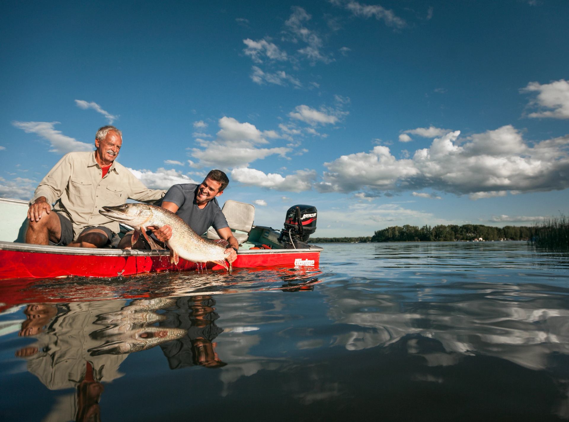 Two men holding a fish on a boat