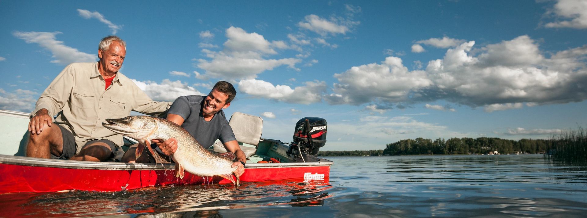 Two men holding a fish on a boat