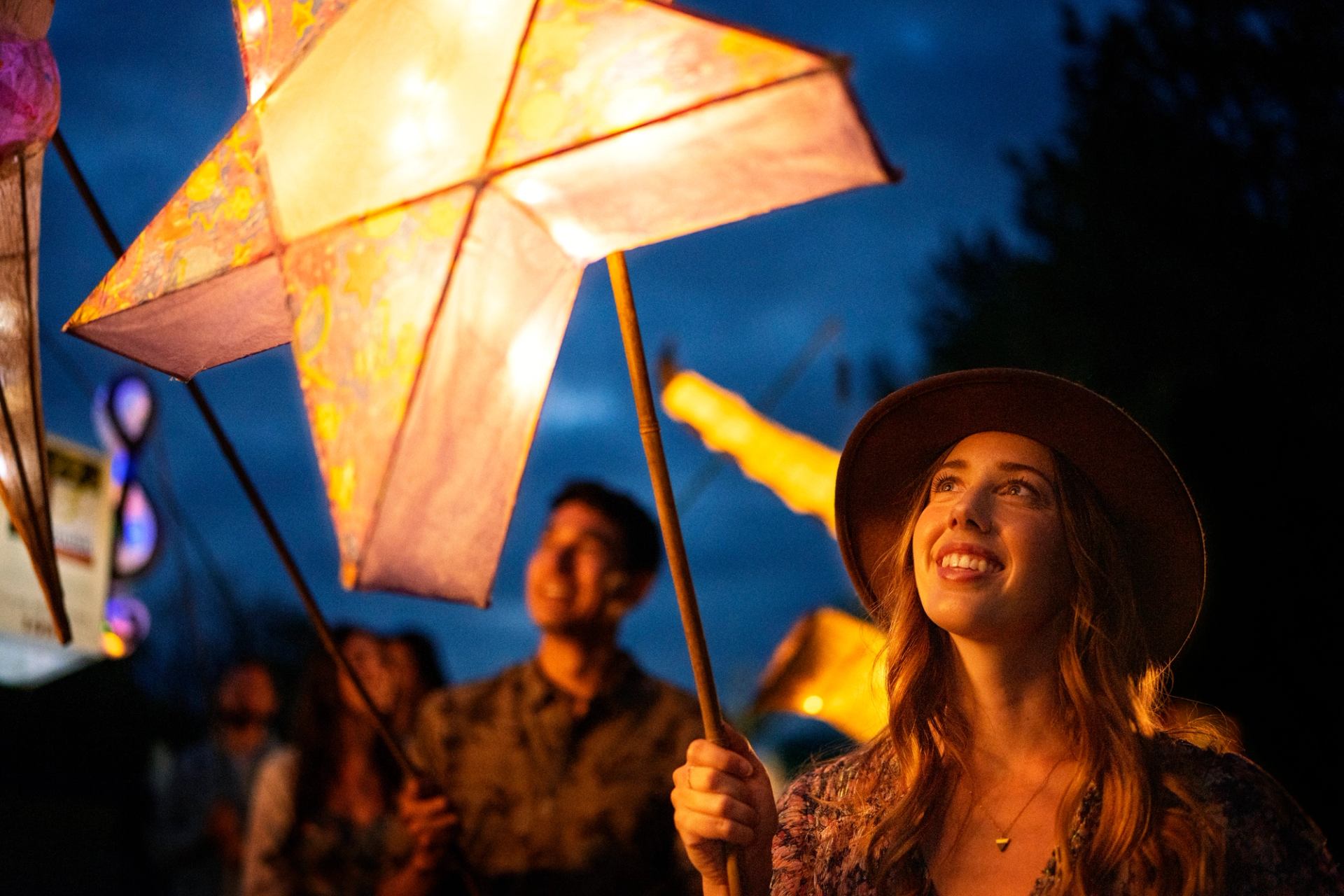 People holding glowing star-shaped lanterns at the Edmonton Folk Music Festival.