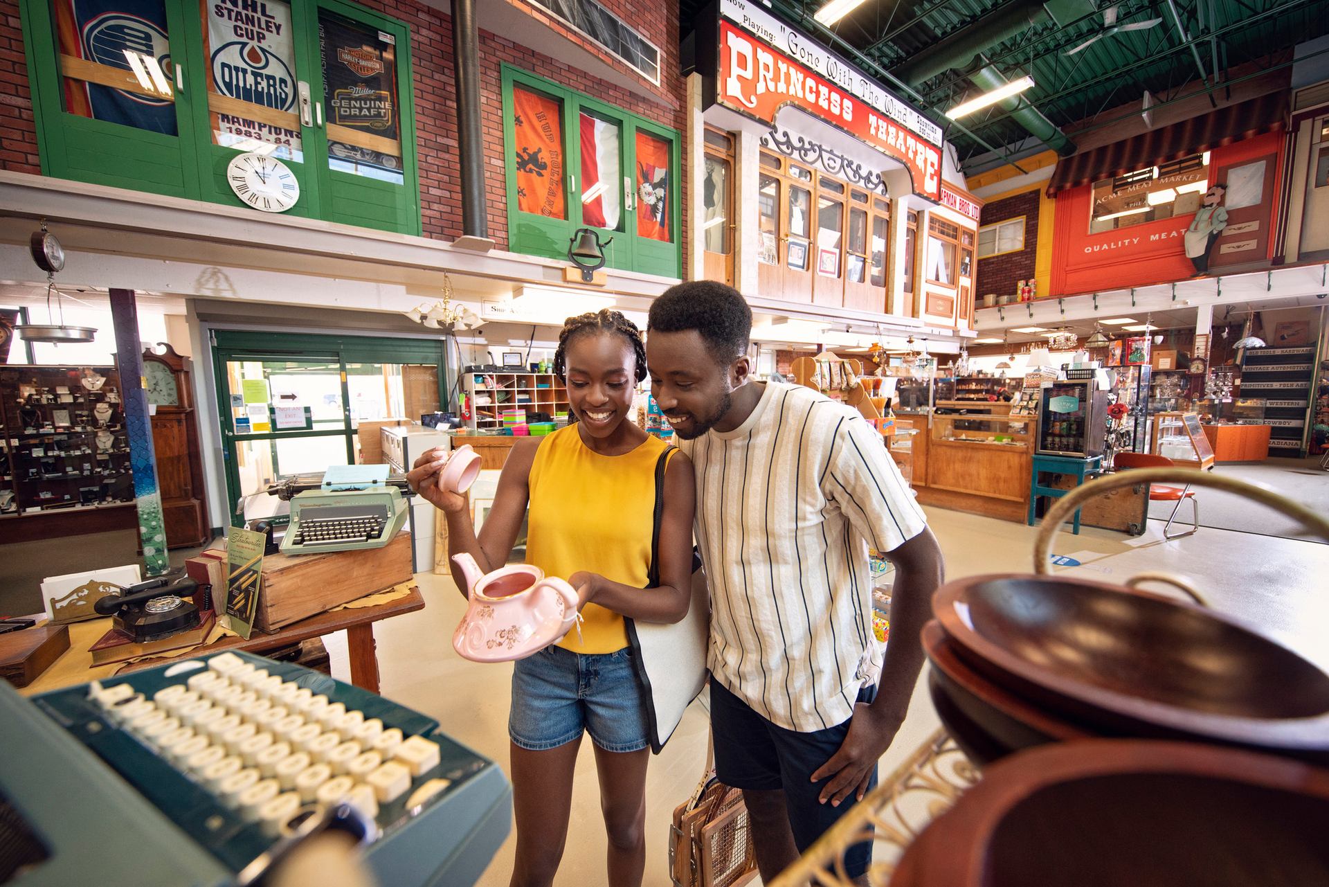 A couple looks at an antique teapot in a large indoor antique mall.