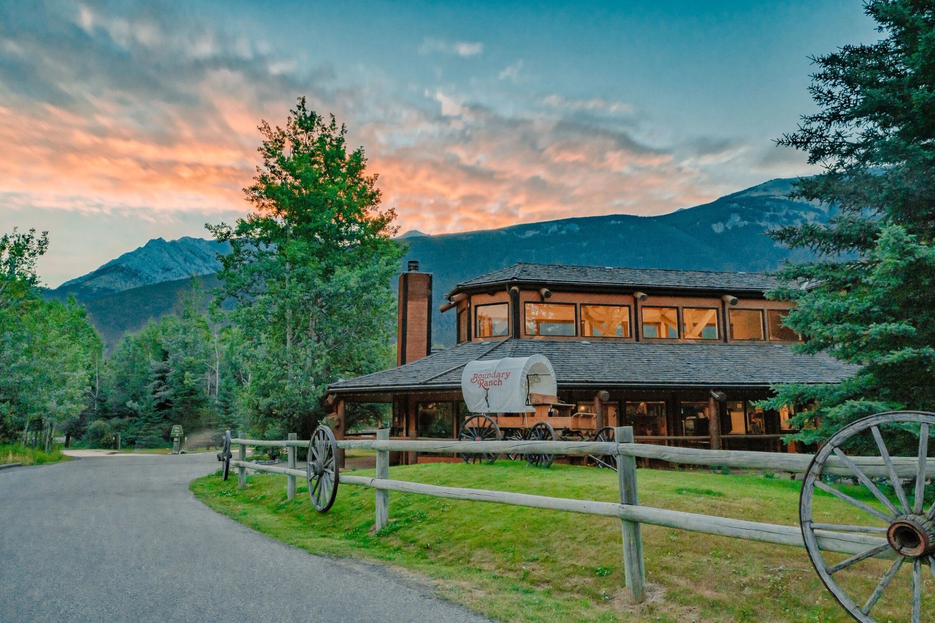 Exterior of building at Boundary Ranch with mountains and a sunset in the background.