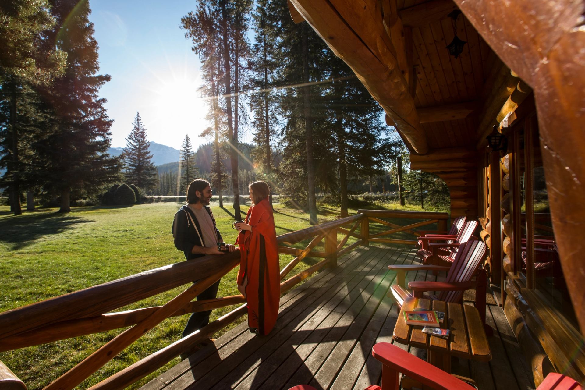 A couple enjoys coffee on the deck of their cabin at Alpine Village Cabin Resort in Jasper, Alberta