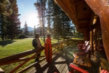 A couple enjoys coffee on the deck of their cabin at Alpine Village Cabin Resort in Jasper, Alberta