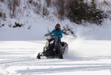 Lone snowmobiler riding through the snow.