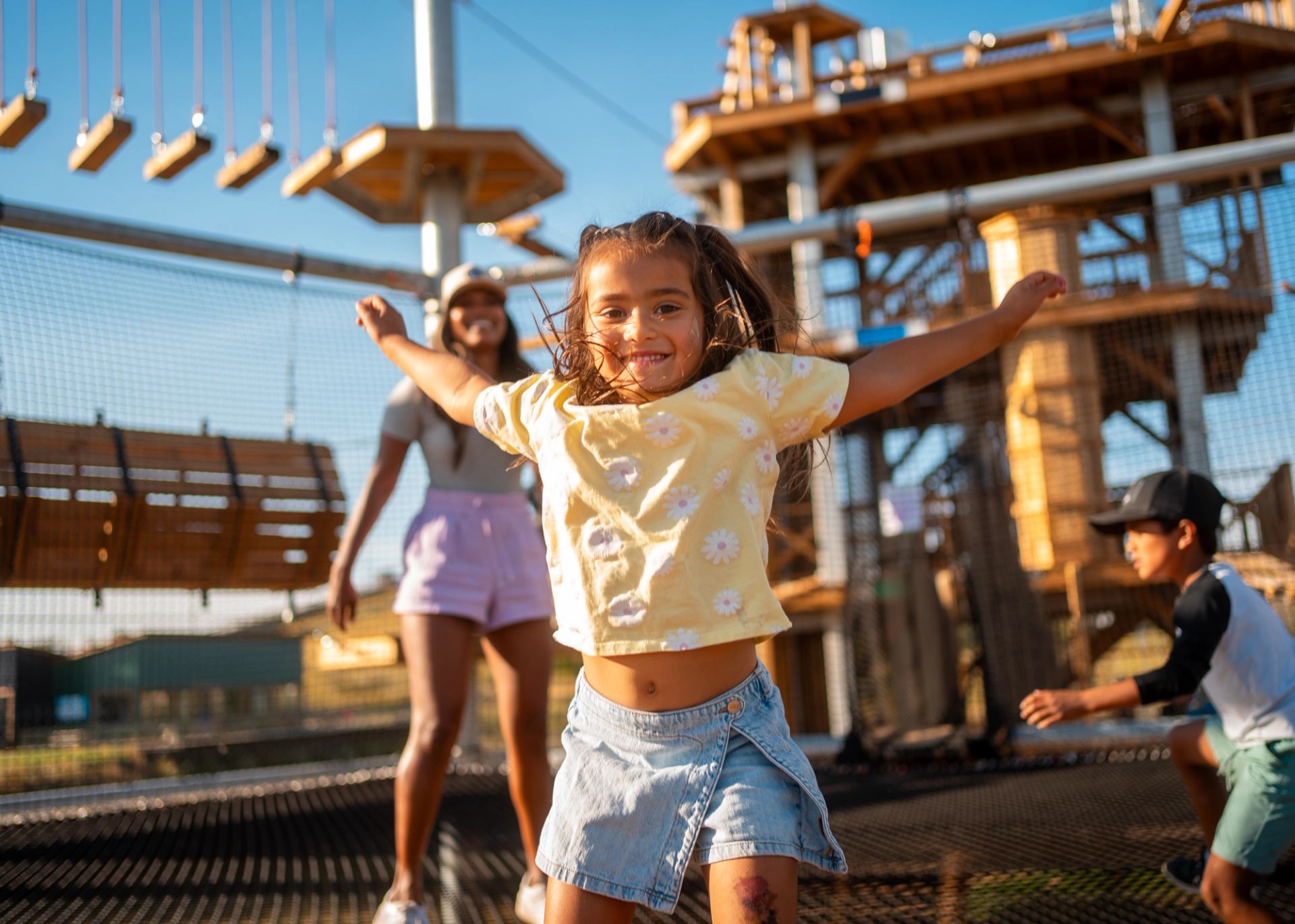 A smiling child jumps on a trampoline surrounded by climbing structures at Canyon Adventure Park in Red Deer.