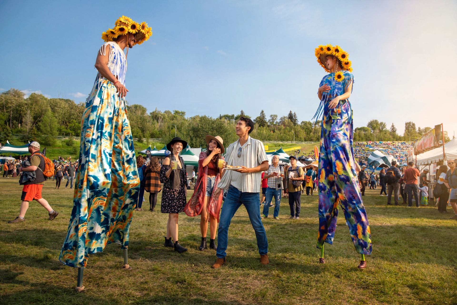 People watch performers on stilts at the Edmonton Folk Music Festival.