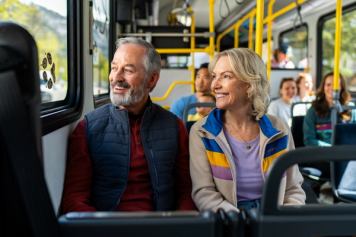 A couple sitting on a Roam Transit bus look outthe window at the mountain views