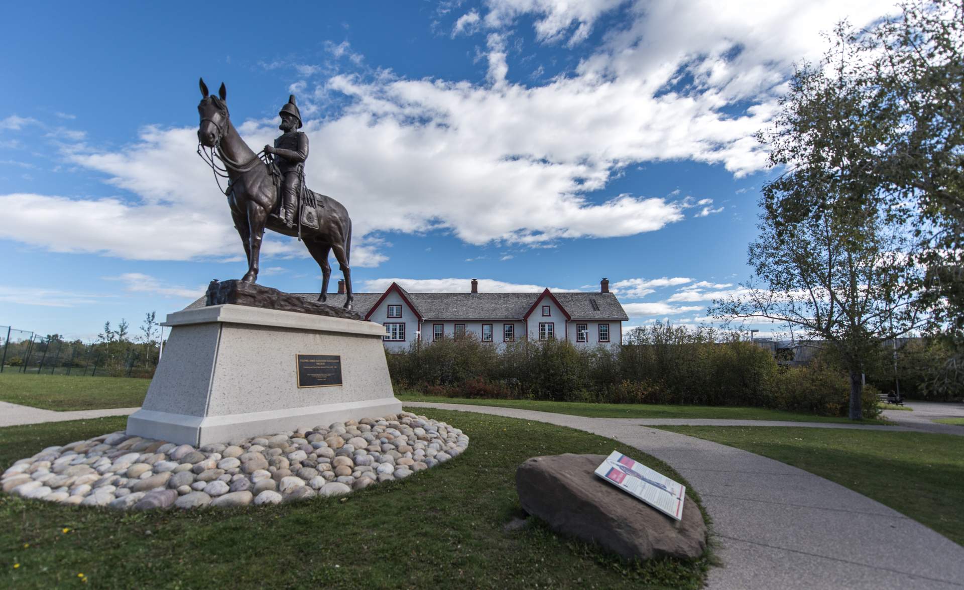 A statue of a horse on a lawn with a historic building.