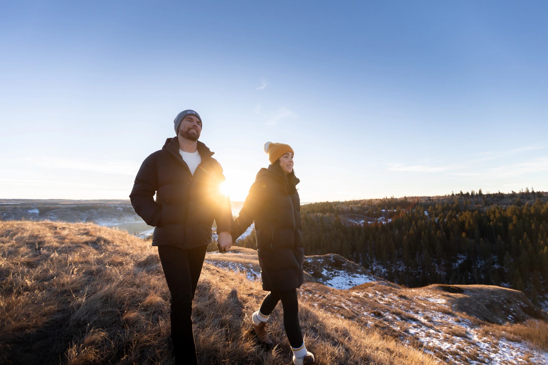 A couple stroll along a snowy hillside near Innisfail.