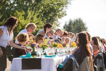 Group of people dining outdoors at a long table at the Taste of Markerville near Red Deer.