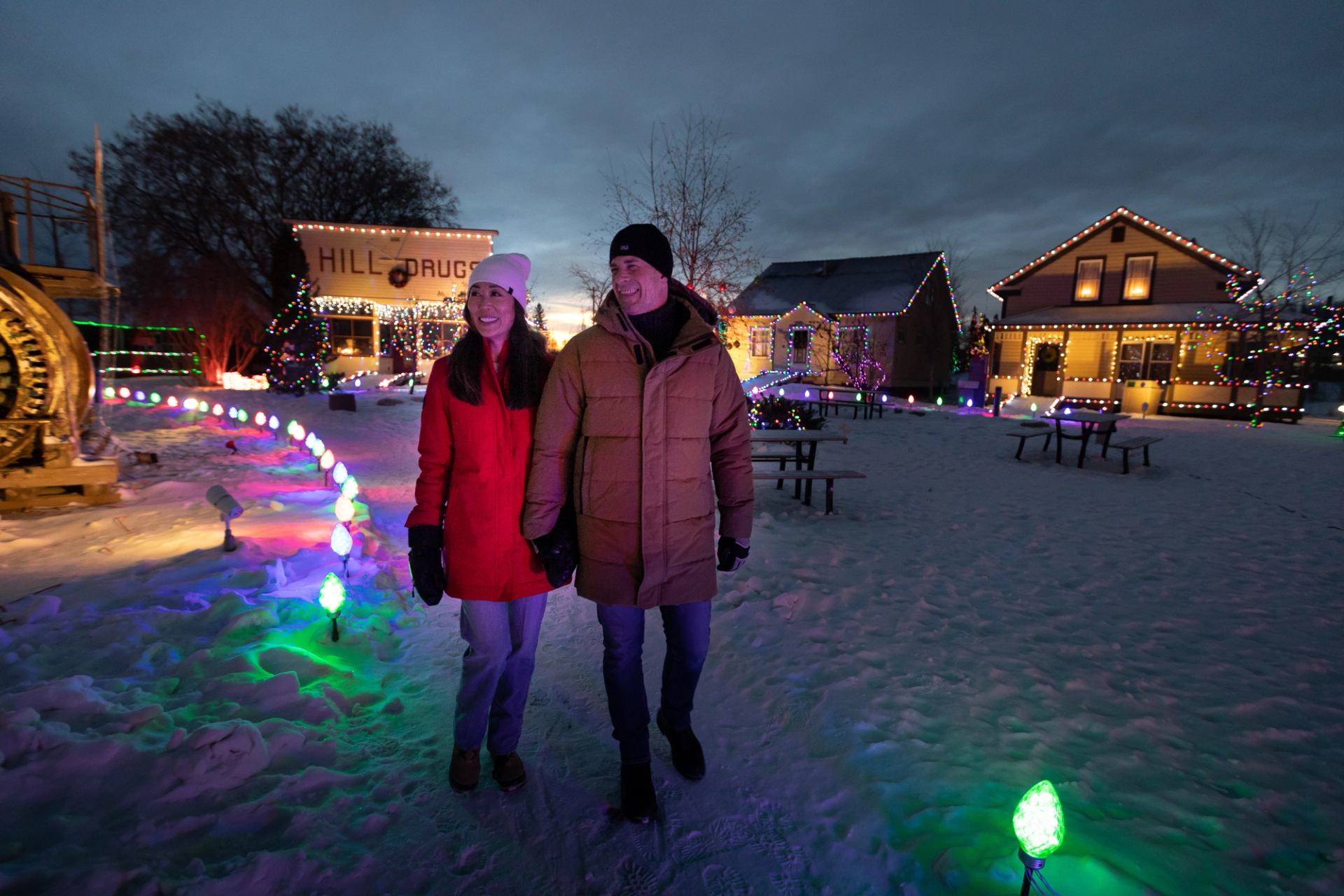 Couple walking through a lit up village at night, at Heritage Village in Fort McMurray
