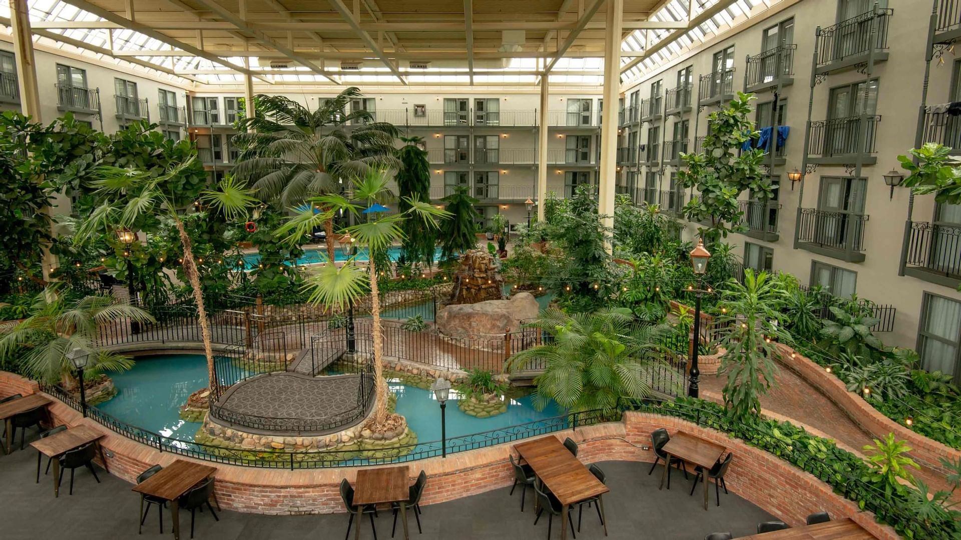 Aerial photo of an indoor pool area of a hotel with a lush garden.