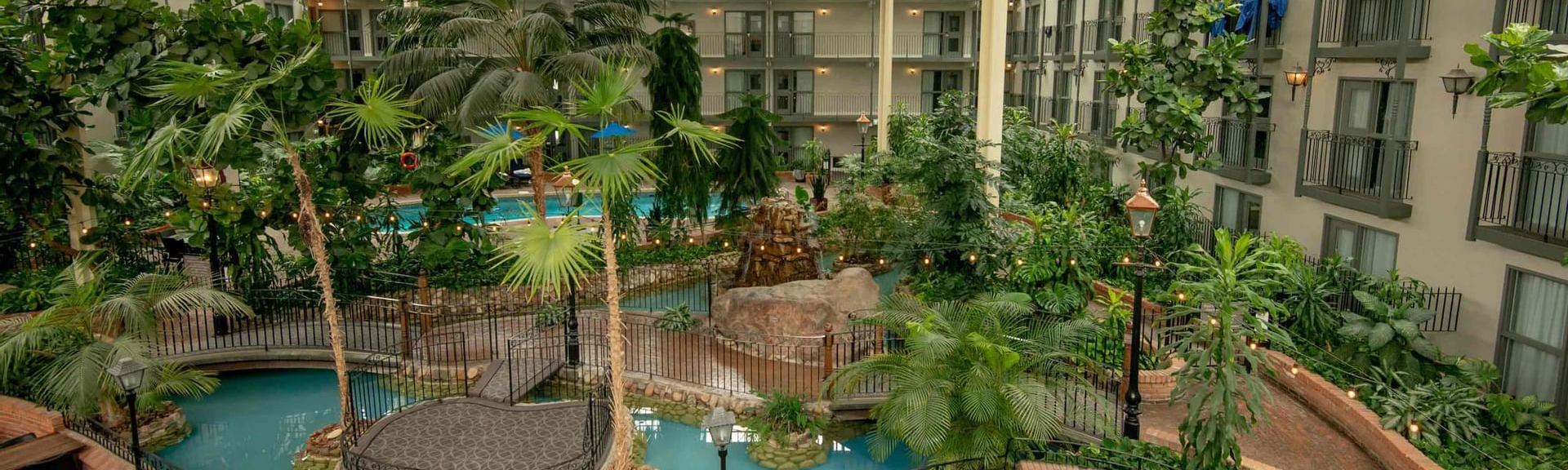 Aerial photo of an indoor pool area of a hotel with a lush garden.