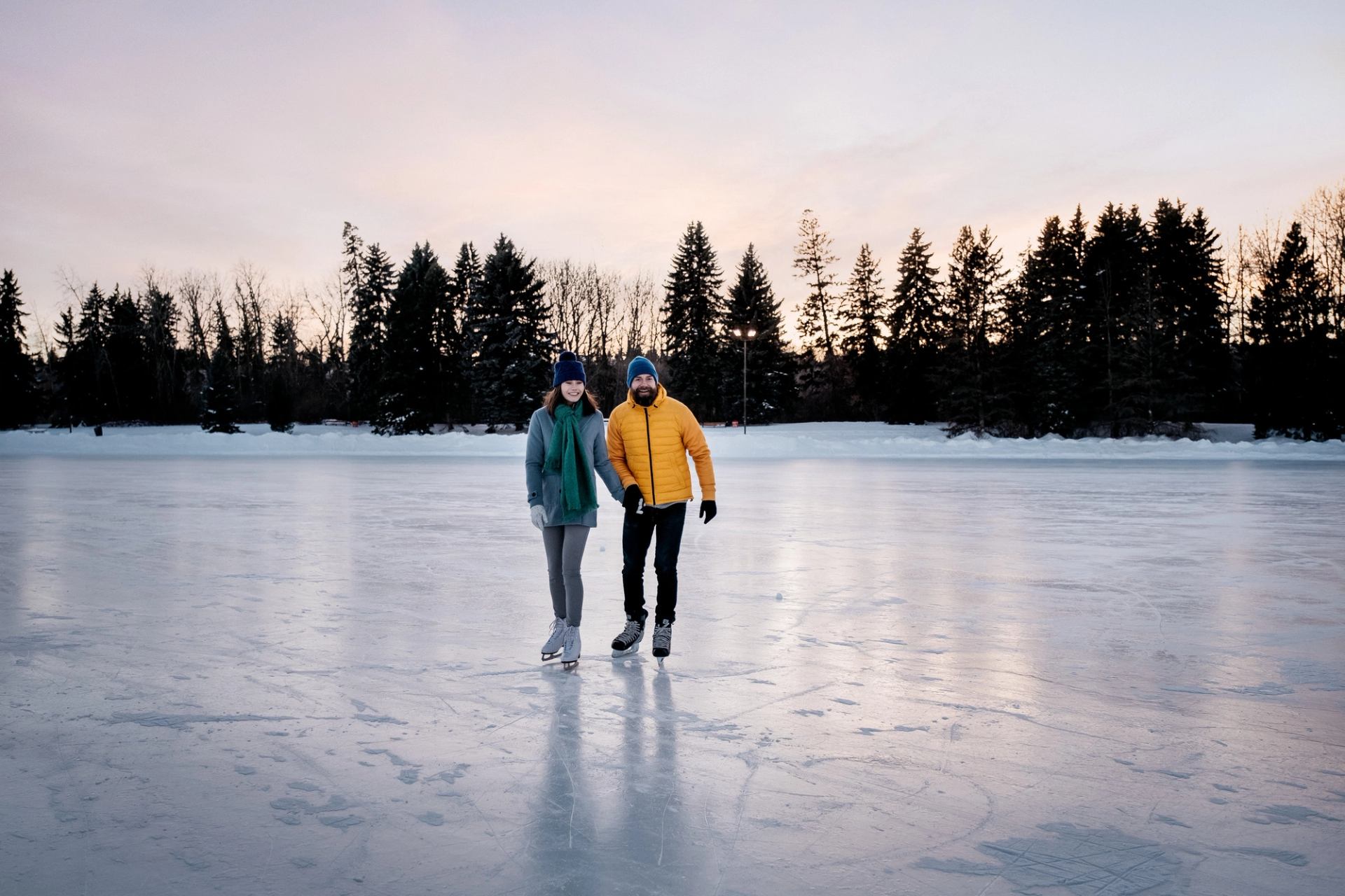 A couple hold hands while ice skating on an outdoor rink/frozen lake at the Silver Skate festival Edmonton.