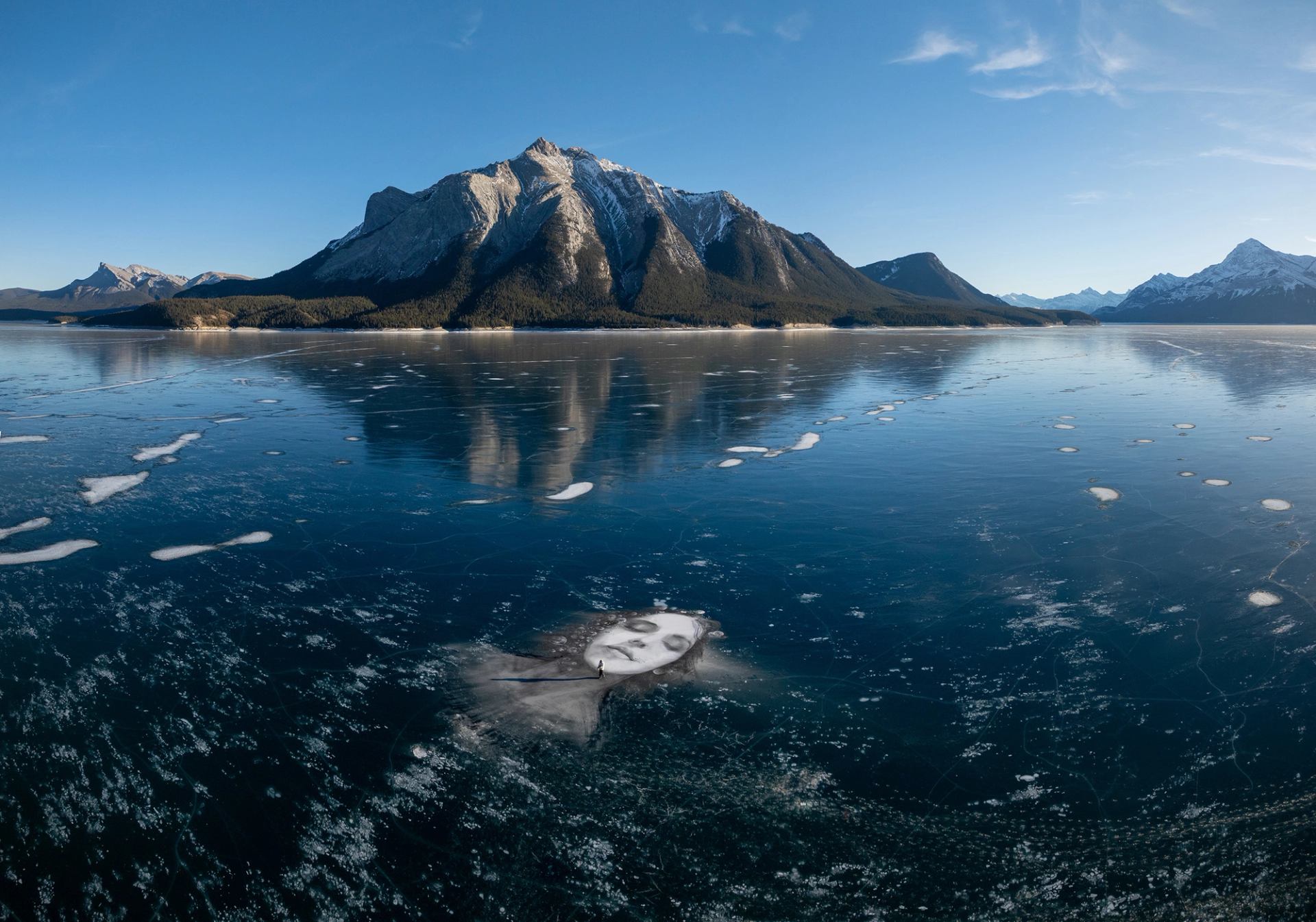 David Popa is tiny in comparison to the huge portrait he painted on the Abraham Lake ice.