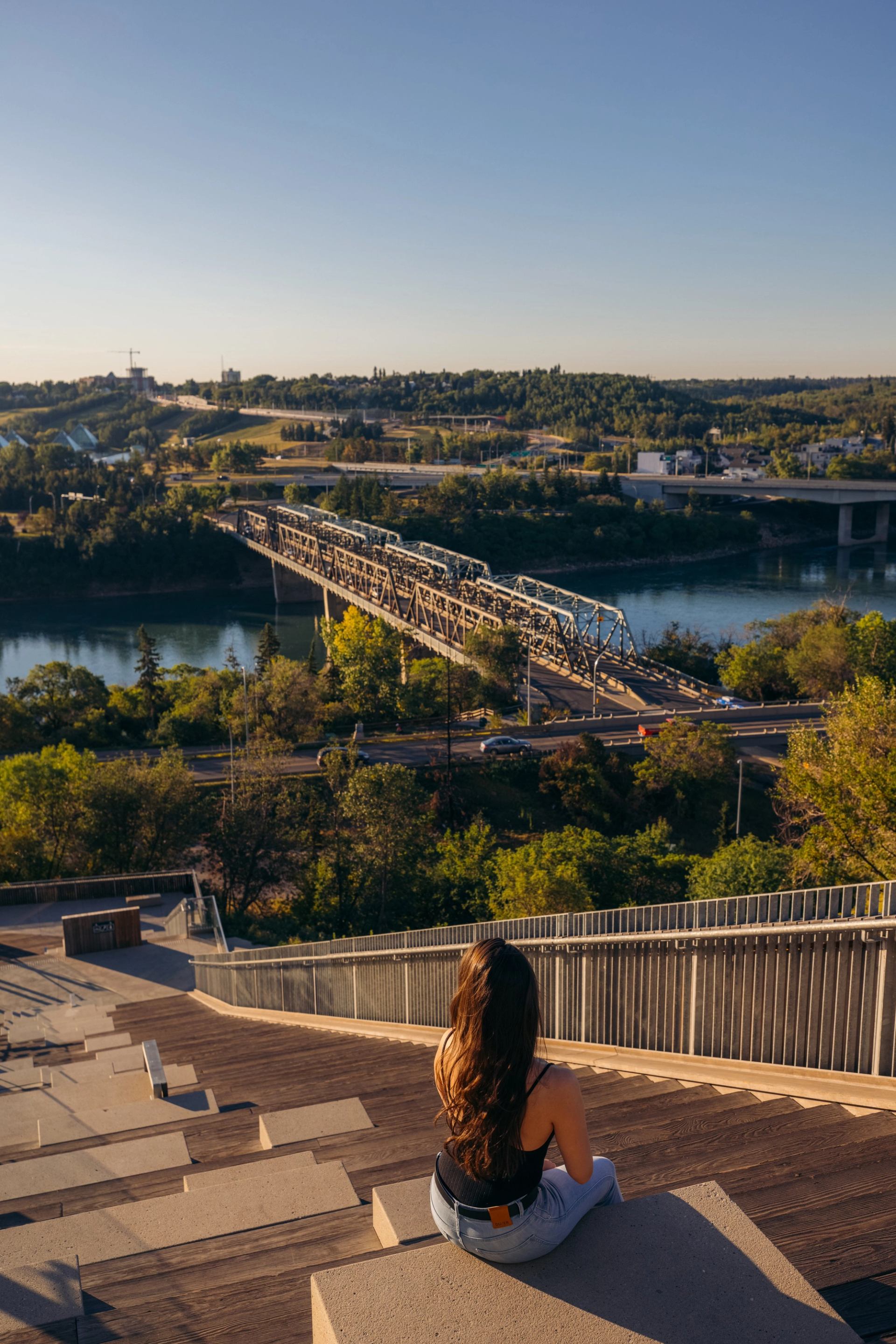 Woman sits on stairs looking at river valley view in Edmonton.