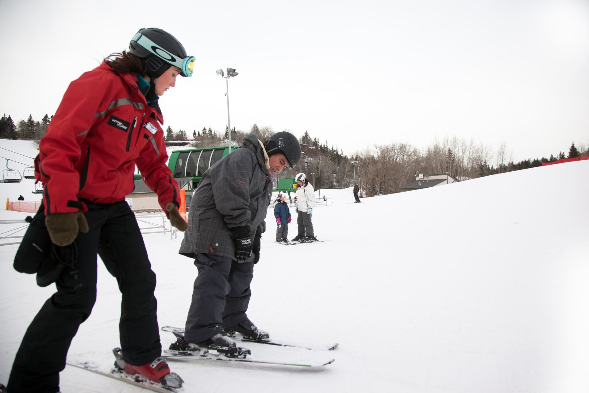 An instructor teaches a boy how to ski at a ski resort.