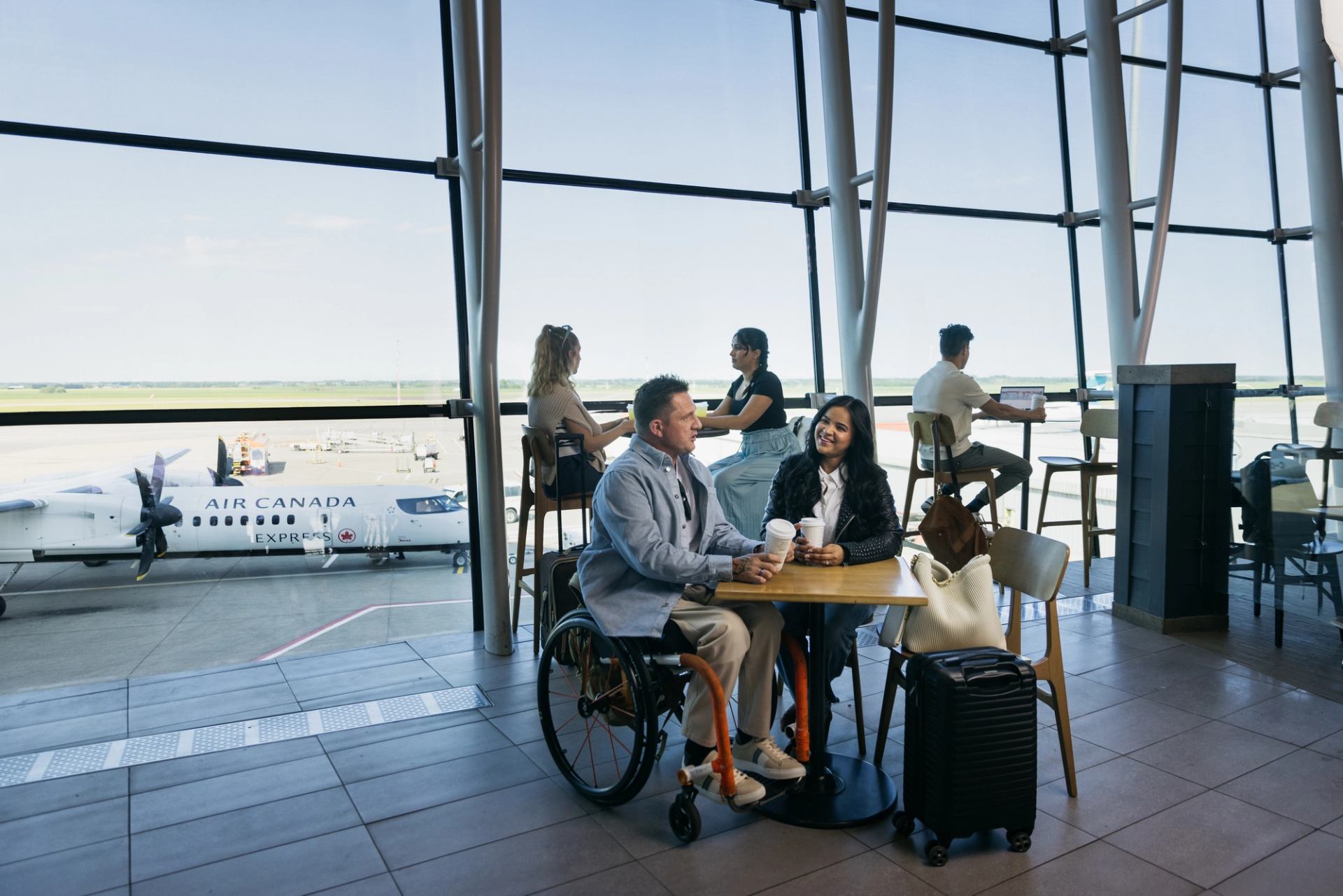 A woman and a man in a wheelchair sit in a casual dining area of Edmonton's airport.