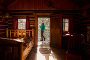 Woman walking outside of her cozy cabin at Storm Mountain Lodge.