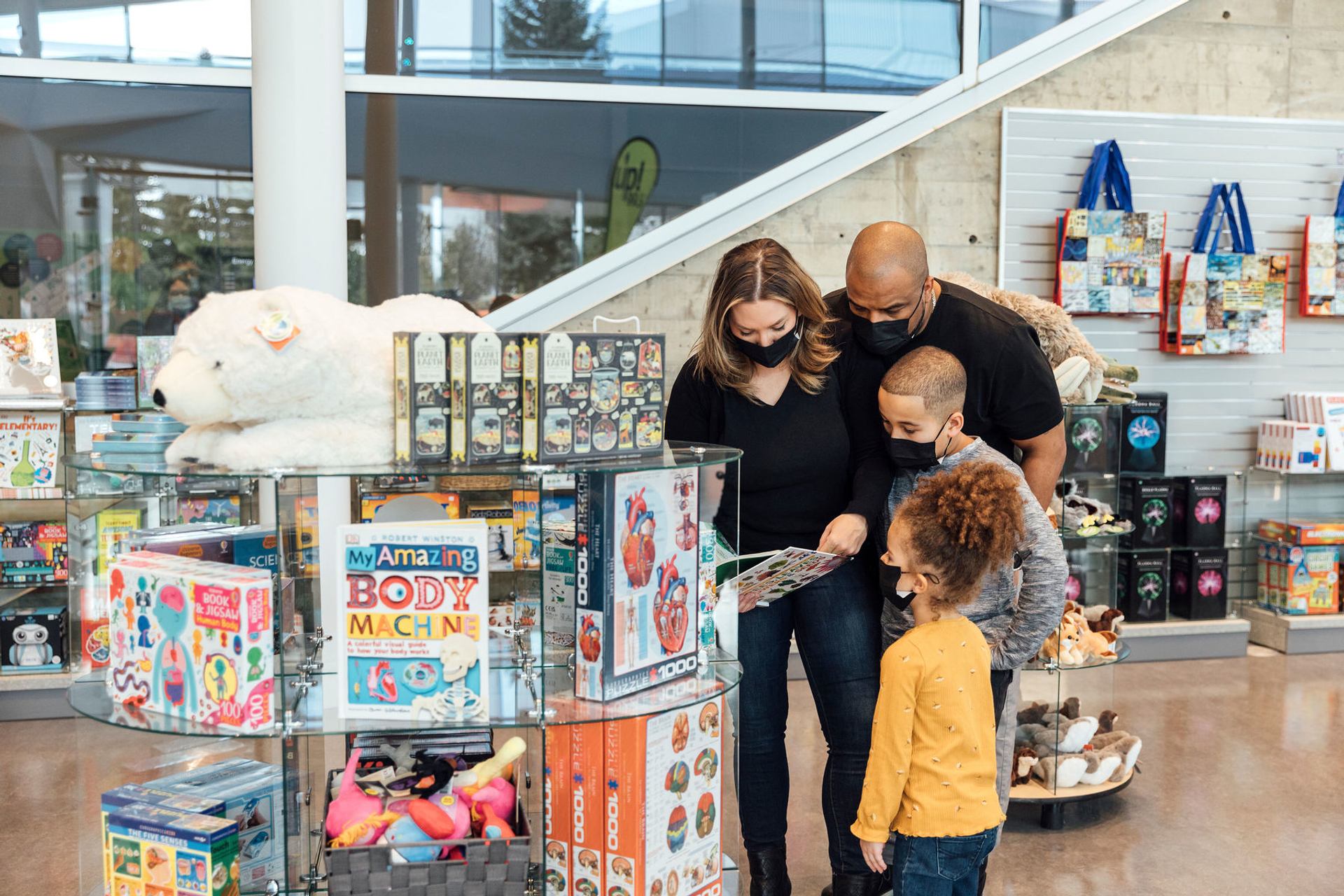 A family checks out a science book from a display in the TELUS World of Science gift shop.