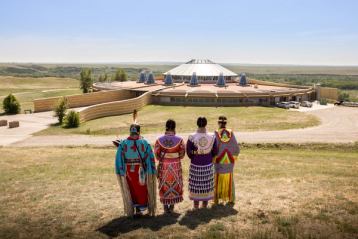 Siksika Blackfoot dancers standing in front of the Blackfoot Crossing Historical Park Interpretive Centre