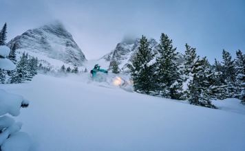 A snowmobiler driving through snow in Crowsnest Pass.