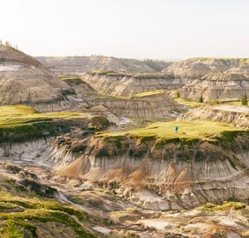 Person and their dog hiking in the badlands amongst epic hoodoos on a summer day