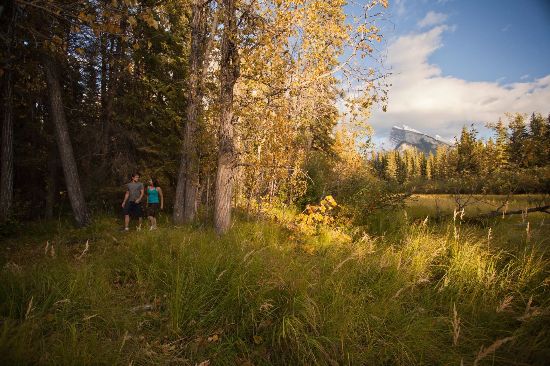 Two people walk through a forested area on Fenland Trail in Banff Alberta.
