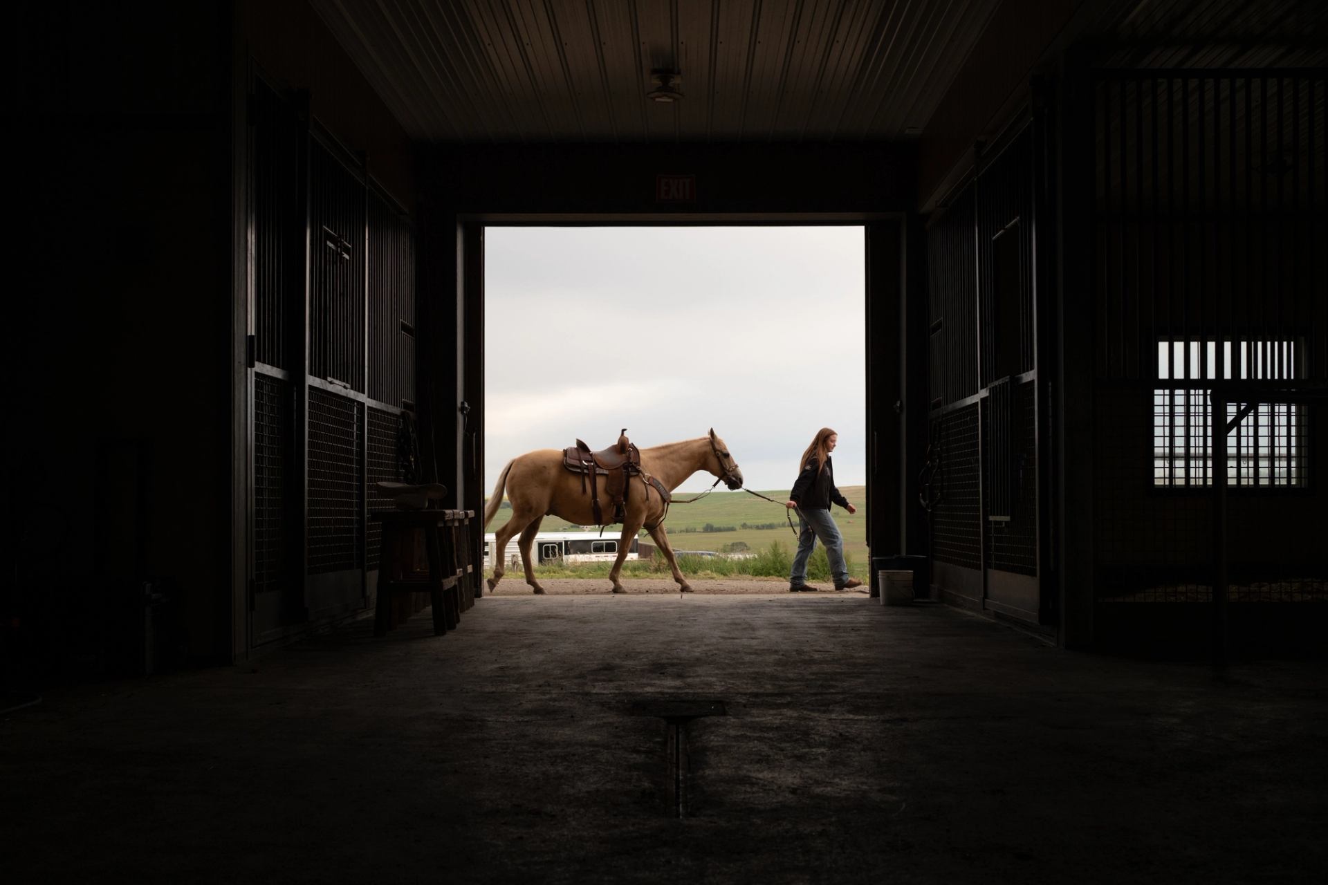 A girl leads a horse past a barn at Christman Family Farm.