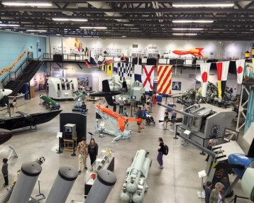 Interior birds eye view of guests looking at military items on a museum floor.