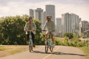 Two people bike along a path in Calgary