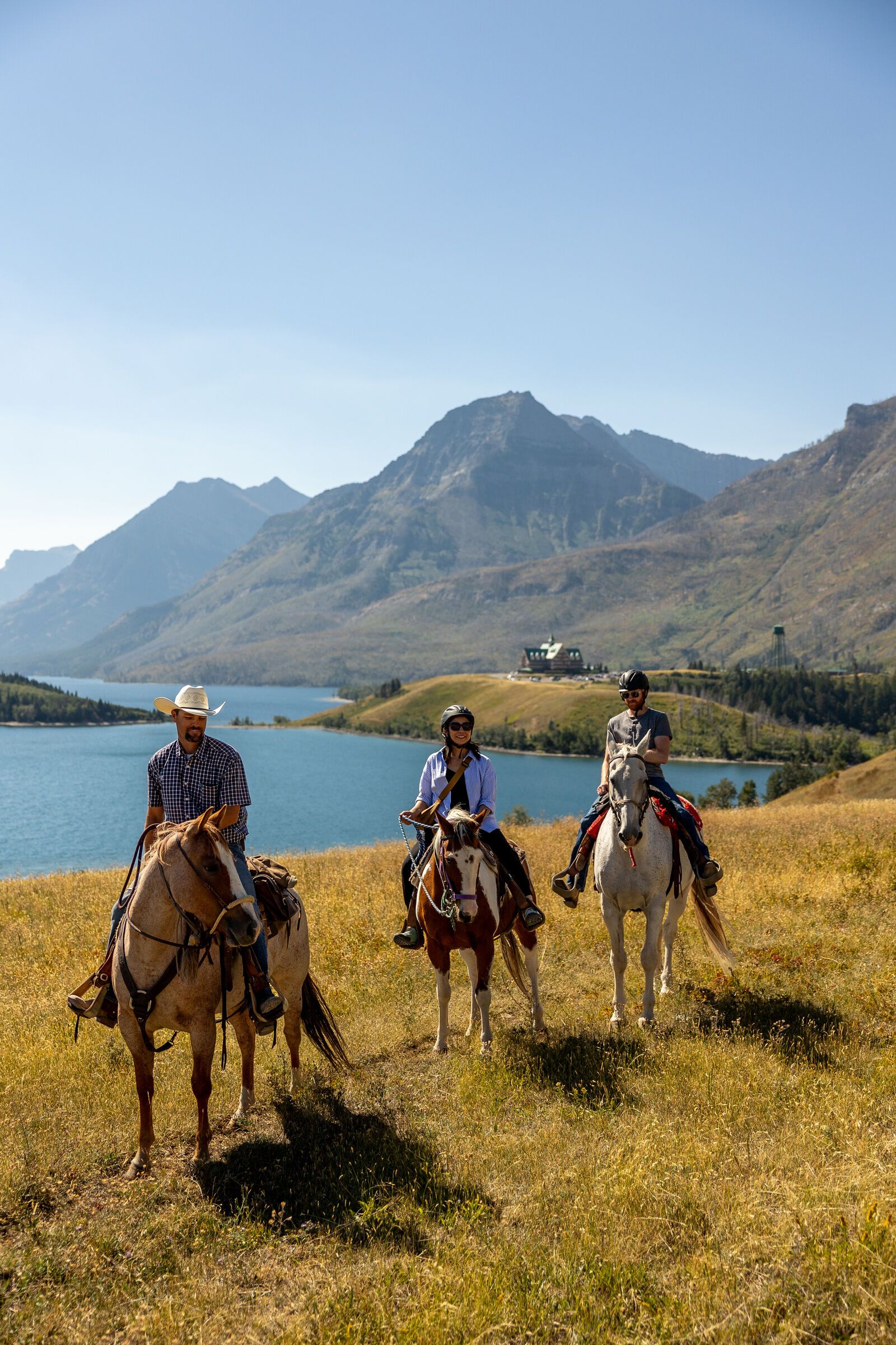 Trailriders stop with their horses in Waterton Lakes National Park with mountains surrounding them.