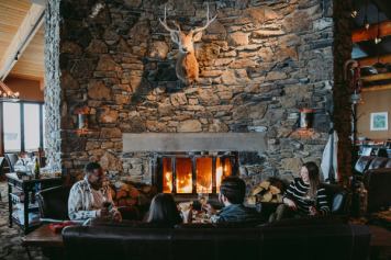 Friends sitting around the fireplace enjoying some drinks at The Chimney Corner Fireside at Sunshine Village in Banff National Park