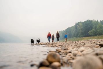 A family and their dogs walk a rocky beach in northern Alberta.
