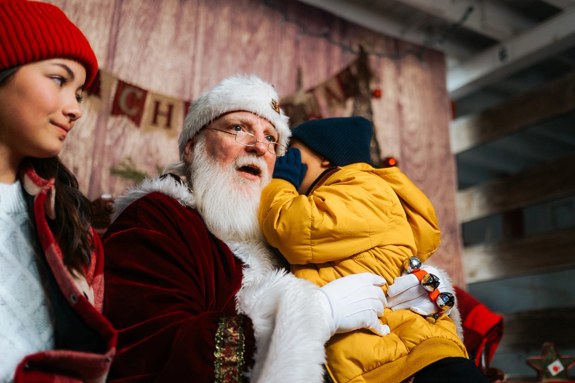 A child sits on Santa’s lap at the Banff Christmas market, whispering Christmas wishes in his ear.