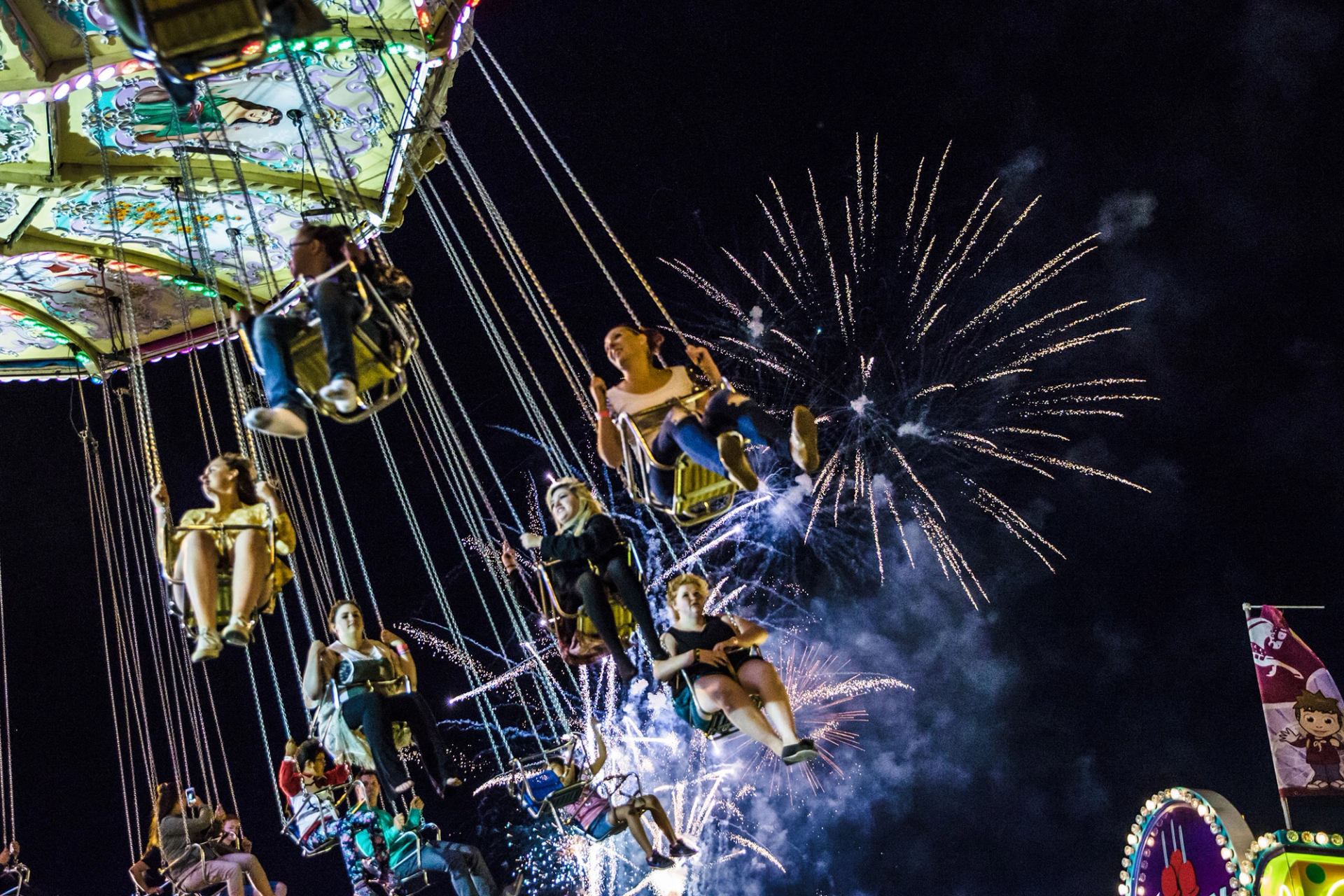 People on a ride with fireworks overhead