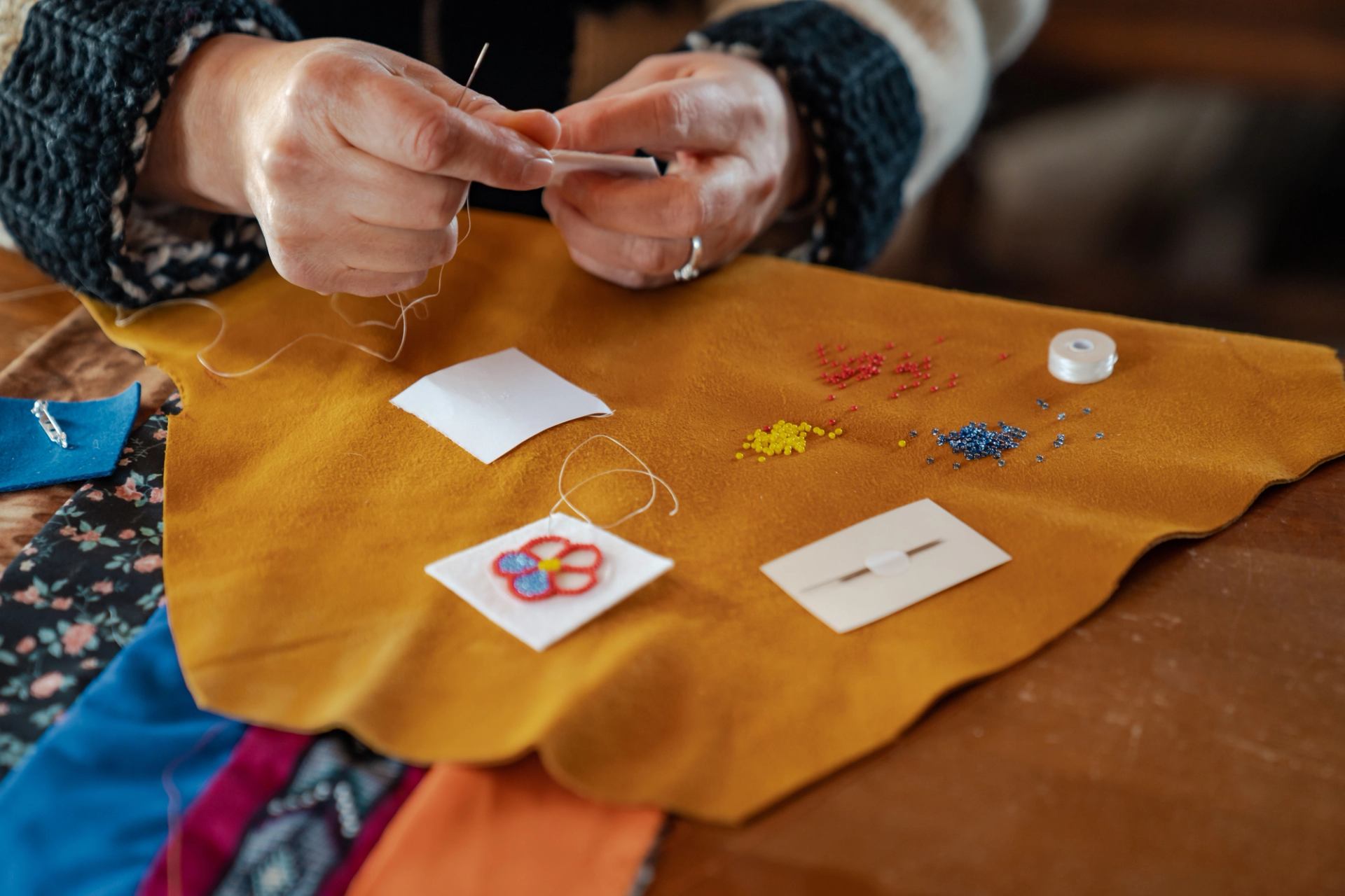 Close up on hands sewing and beading Indigenous art.