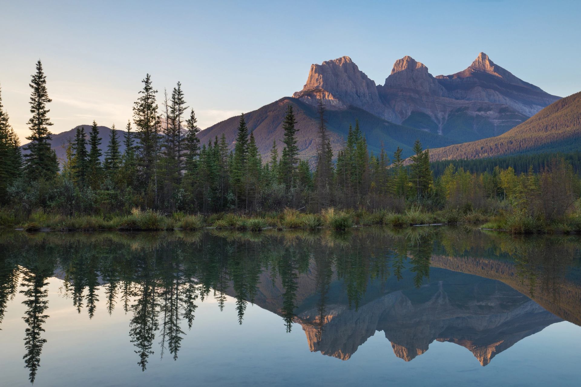 Canmore landscape shot of a lake with a mountain backdrop drenched in evening sun.