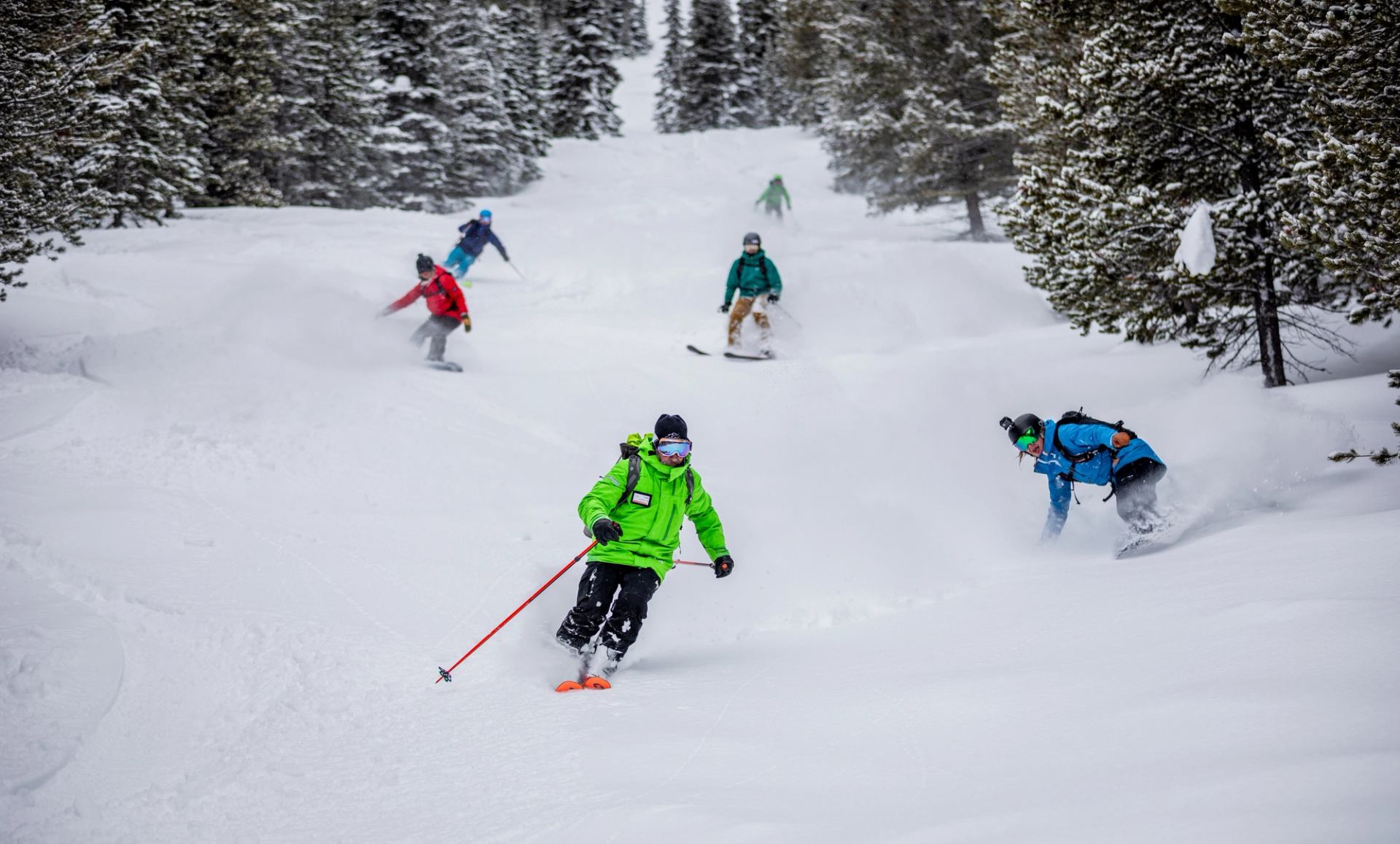 A group of skier and snowboarder attempt a mogul run through the trees while skiing at Castle Mountain Resort