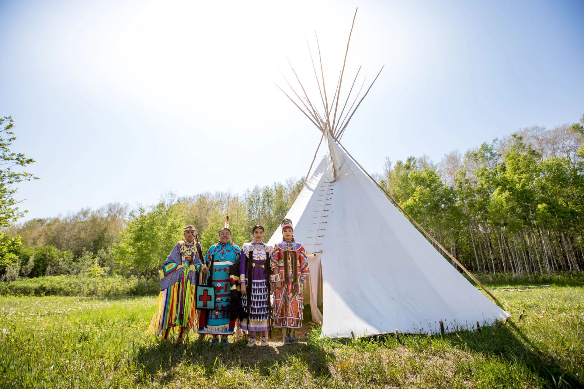 Siksika Blackfoot dancers standing in front of a tipi in Tipi Village