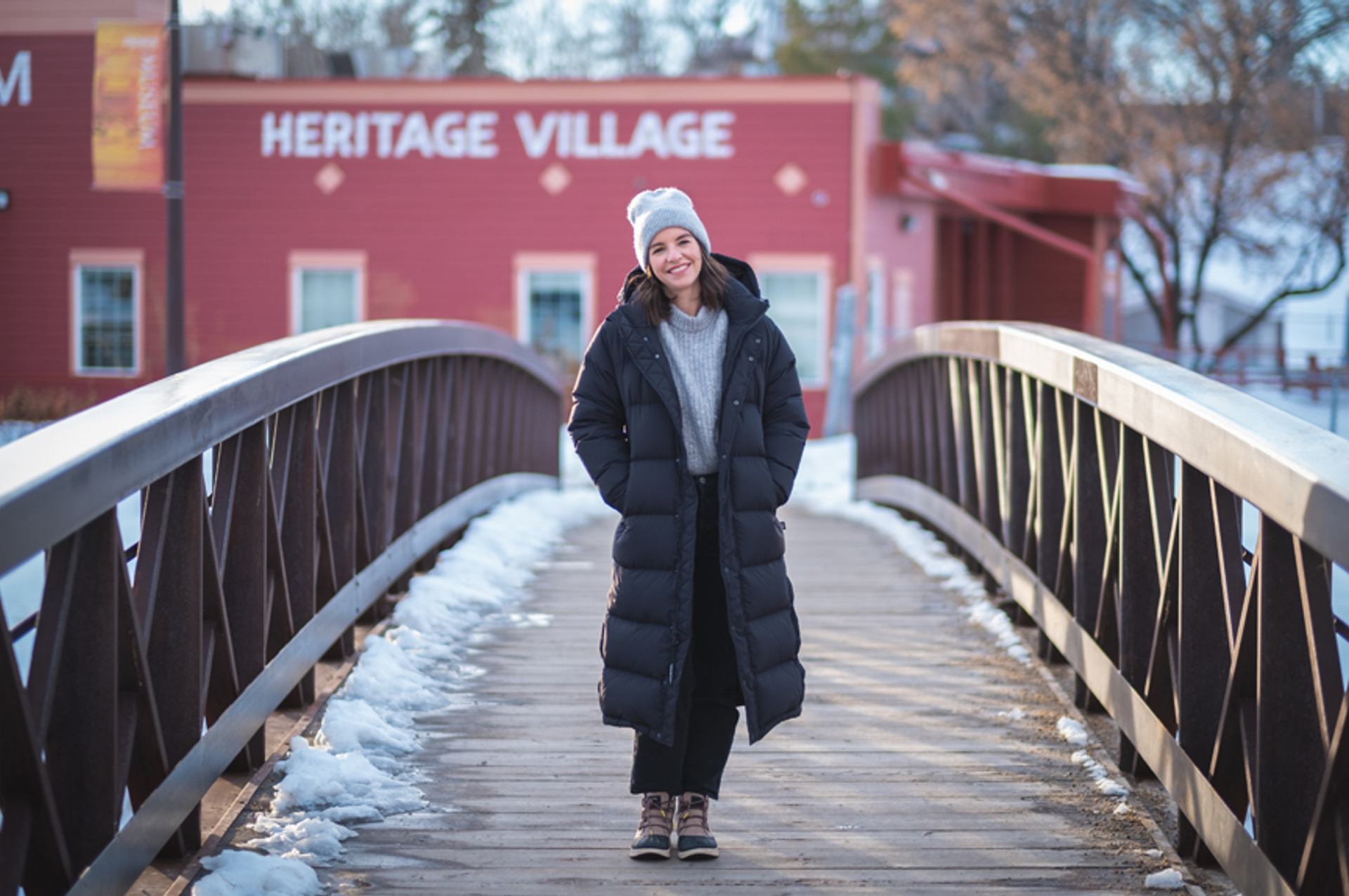 Woman standing on a bridge with a building in the background.