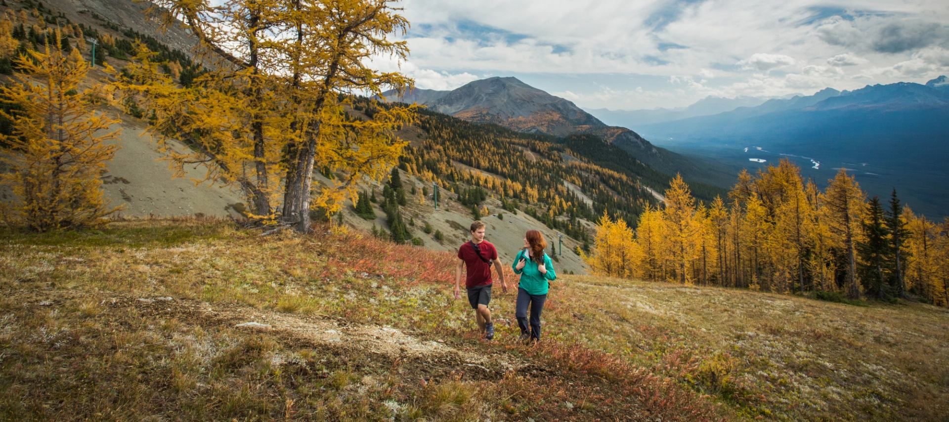 Couple hiking through the autumn colours in the mountains.