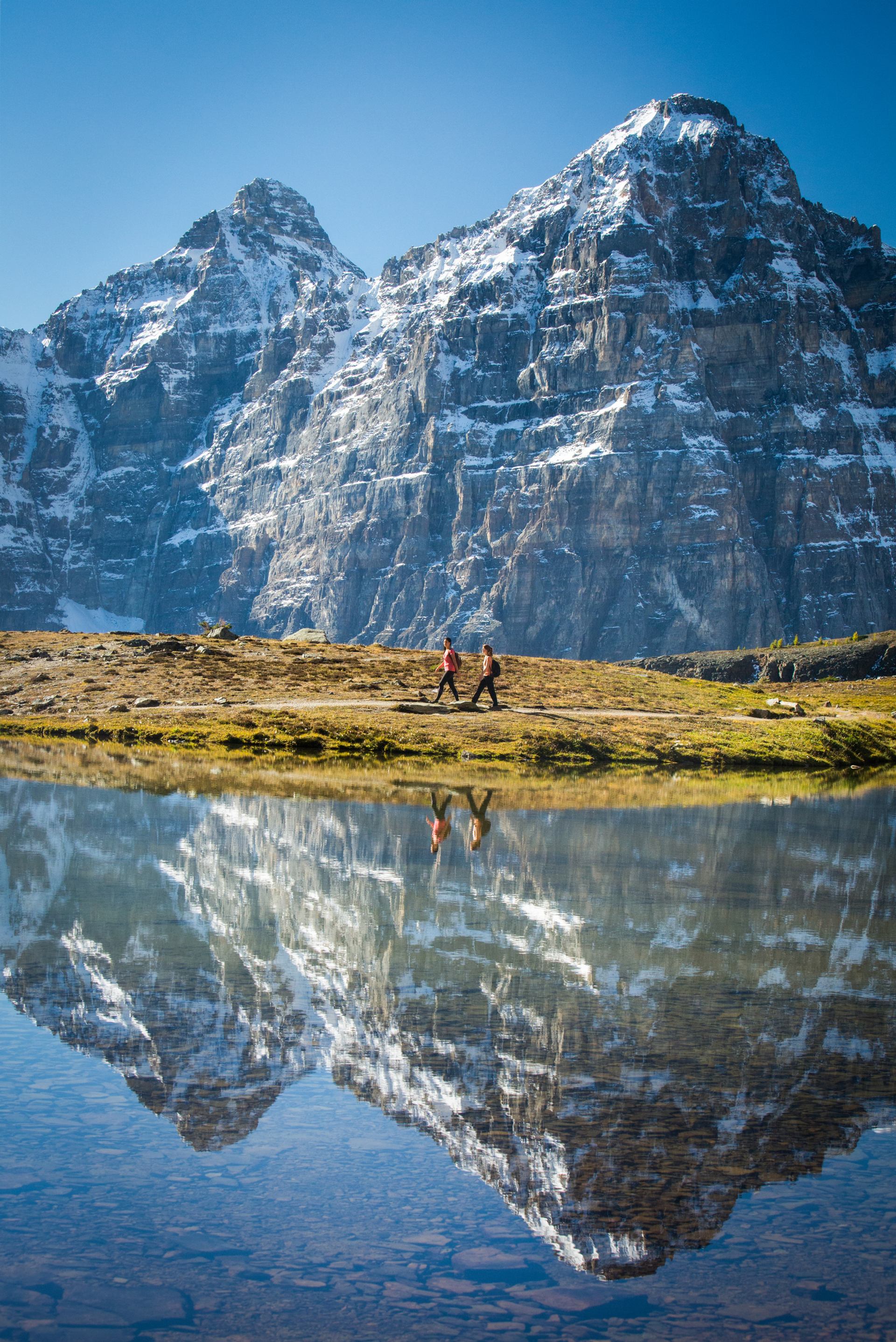 Hikers walk along the water on the Sentinel Pass Trail in Banff National Park.