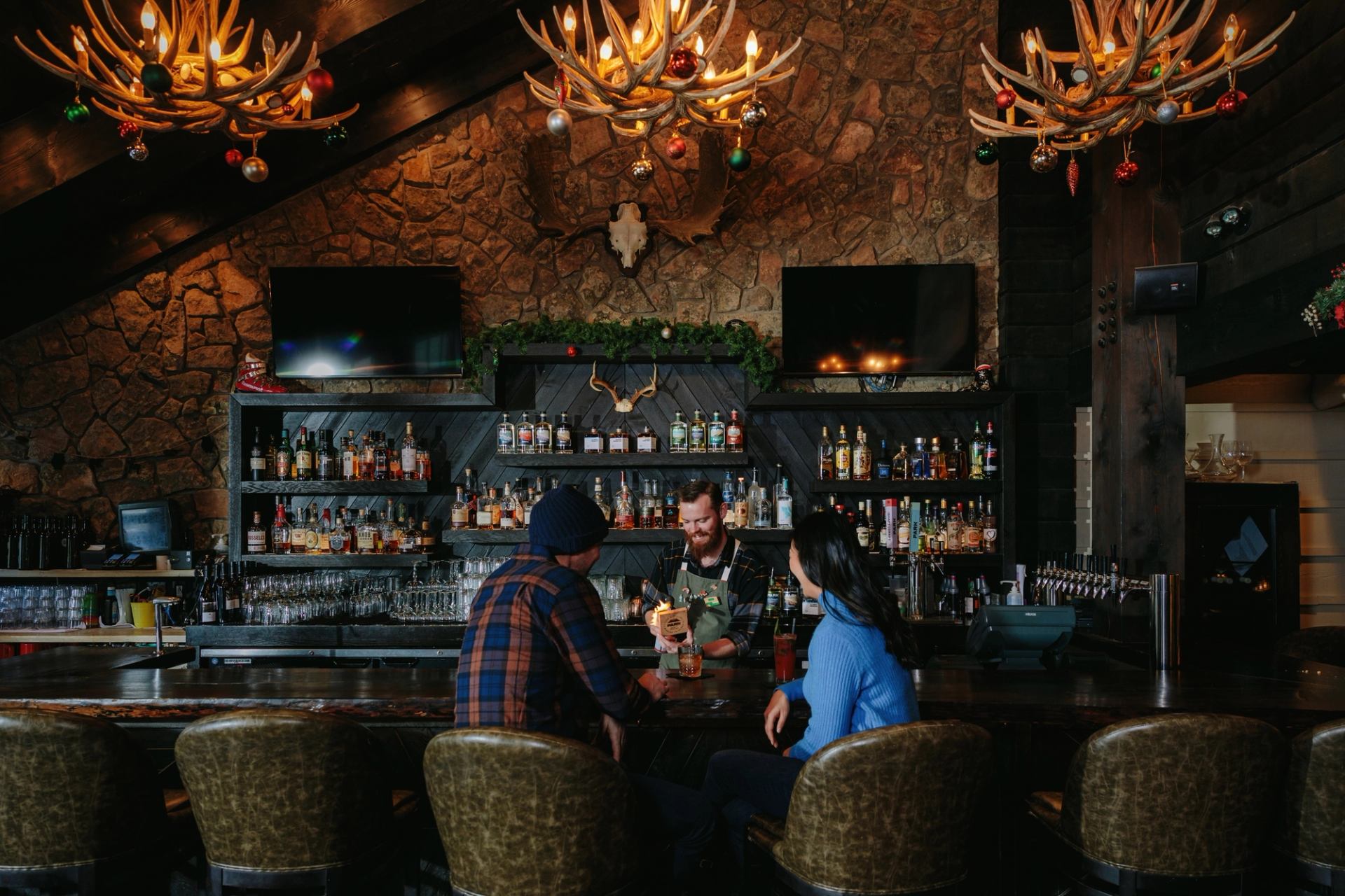 A couple sitting at the bar enjoying drinks at Park Distillery in Banff National Park.