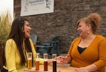 Two women laugh while enjoying a flight of beers on Theoretically Brewing Co.'s patio in Lethbridge.