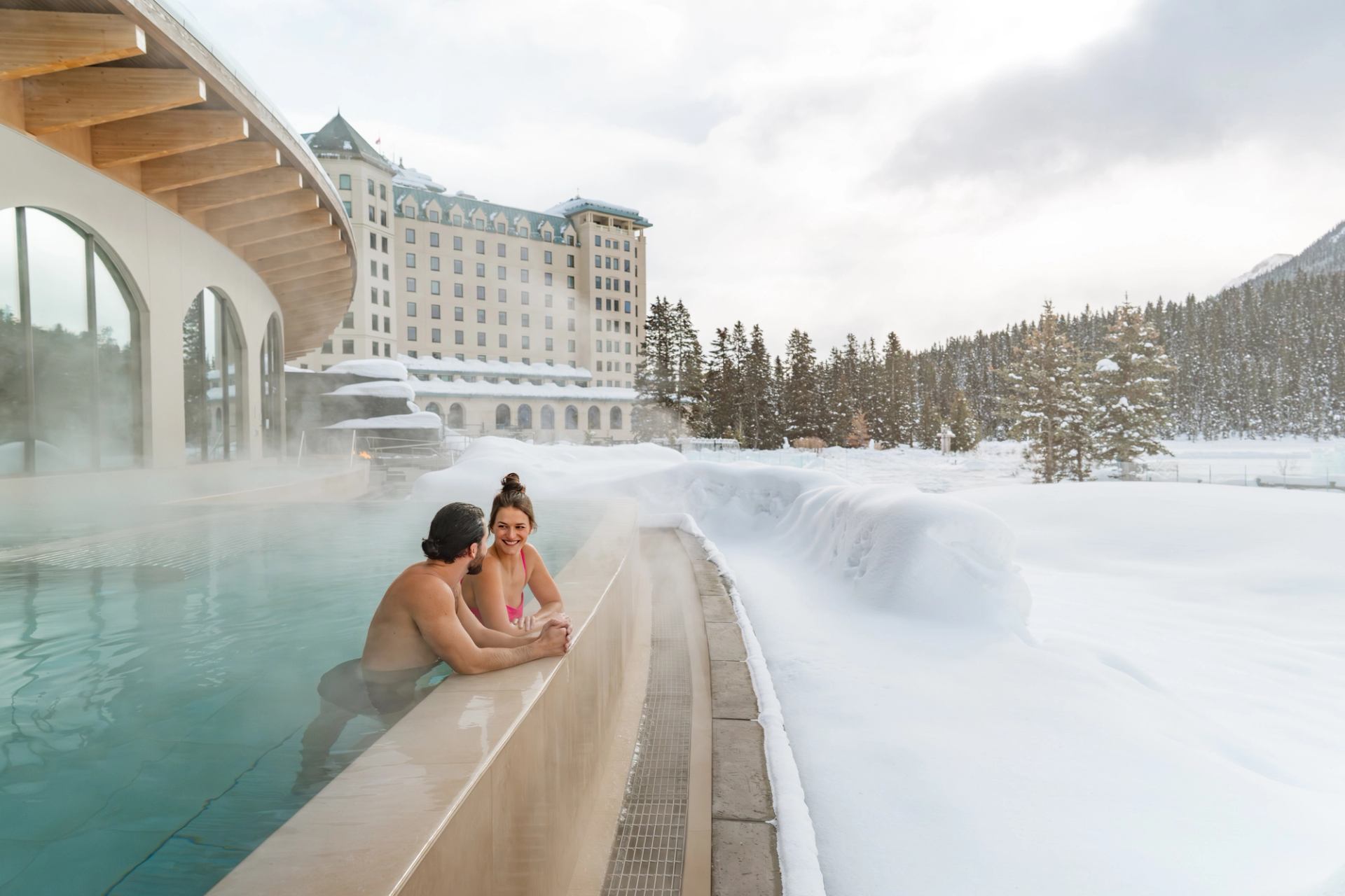A couple enjoy the view from an outdoor hot tub at BASIN Glacial Waters Spa at Fairmont Chateau Lake Louise.
